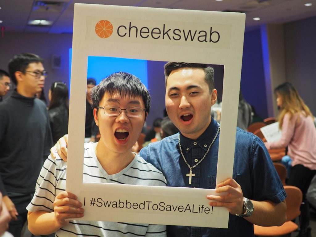 Two East Asian men smiling into Cheekswab frame